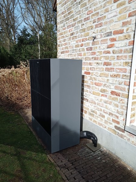 De buitenunit van opzij, met de afvoer van het condenswater